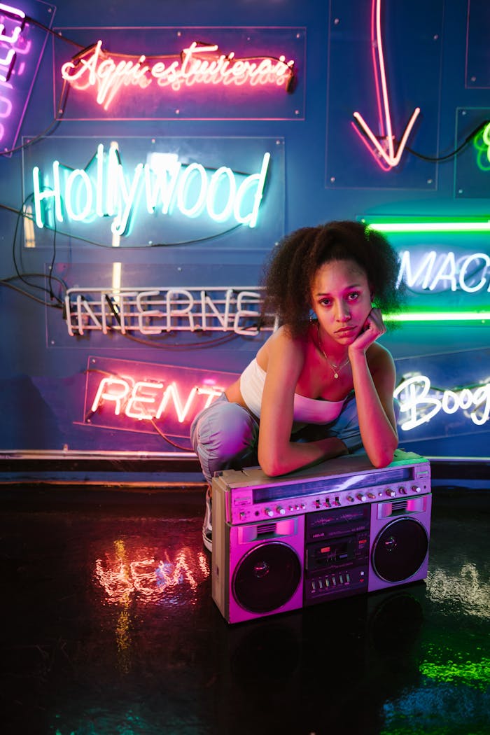 our-story Young woman in a neon-lit room with a vintage boombox, embodying vibrant nightlife and urban culture.